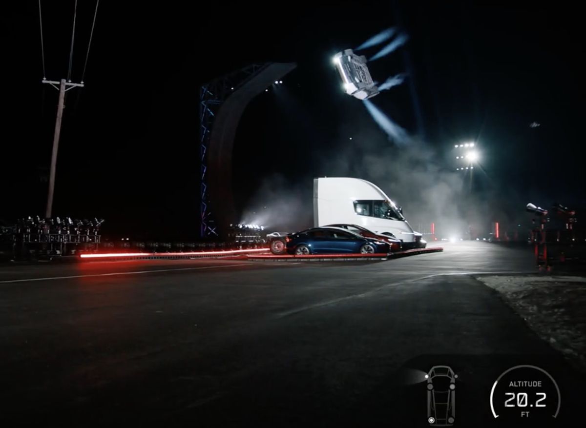 At night, a Tesla Roadster hangs in midair with thruster plumes streaming behind it, above a Tesla Semi and two parked cars; the livestream's readout says altitude 20.2 feet.
